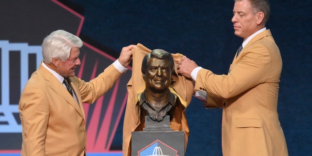 Jimmy Johnson, left, a member of the Pro Football Hall of Fame Centennial Class, unveils his bust with his presenter, Troy Aikman, during the induction ceremony at the Pro Football Hall of Fame, Saturday, Aug. 7, 2021, in Canton, Ohio. (Associated Press)