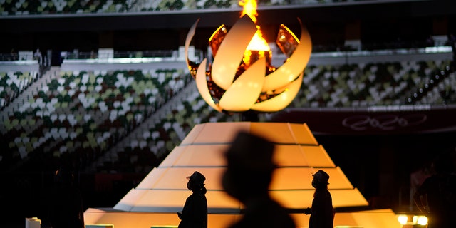 Volunteers stand as the President of the International Olympic Committee, Thomas Bach, delivers a speech during the closing ceremony at the Olympic Stadium for the 2020 Summer Olympics on Sunday, August 8, 2021, in Tokyo, Japan.  (AP Photo / David Goldman)