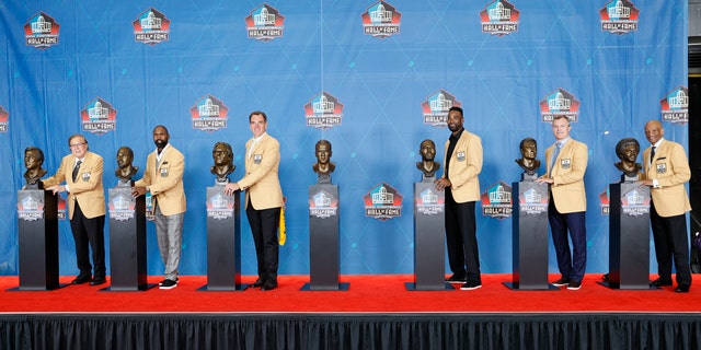 From left to right, Tom Flores, Charles Woodson, Alan Faneca, Calvin Johnson, John Lynch and Drew Pearson pose with their busts during the induction ceremony at the Pro Football Hall of Fame, Sunday, Aug. 8, 2021, in Canton, Ohio. Peyton Manning, whose bust is at center, was not present. (AP Photo/Ron Schwane, Pool)