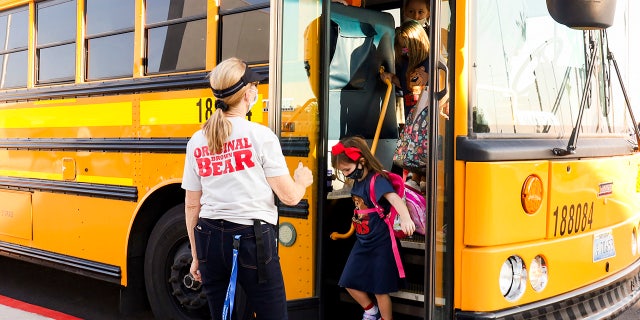 Um professor cumprimenta os alunos quando eles descem de um ônibus no primeiro dia de aula na nova Hannah Marie Brown Elementary School em Henderson, Nevada, segunda-feira, 9 de agosto de 2021. As portas abriram na segunda-feira em escolas em Las Vegas e arredores, onde Máscaras foram exigidas para os mais de 300.000 alunos e cerca de 18.000 professores que retornaram às aulas presenciais no quinto maior distrito do país. (Yasmina Chavez / Las Vegas Sun via AP)