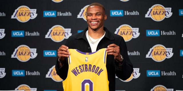 Los Angeles Lakers guard Russell Westbrook poses for a photo with his jersey at an introductory NBA basketball news conference in Los Angeles, Tuesday, Aug. 10, 2021.