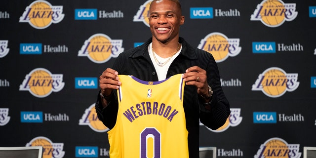 Los Angeles Lakers guard Russell Westbrook poses for a photo with his jersey at an introductory NBA basketball news conference in Los Angeles, Tuesday, Aug. 10, 2021.