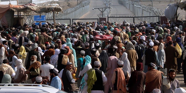 Stranded people gather to seek information from security forces about opening the border crossing between Pakistan and Afghanistan which was closed by authorities a few days ago in Chaman, Pakistan, Wednesday, Aug. 11, 2021. Normally thousands of Afghans and Pakistanis cross daily and a steady stream of trucks passes through, taking goods to landlocked Afghanistan from the Arabian Sea port city of Karachi in Pakistan. (AP Photo/Jafar Khan)