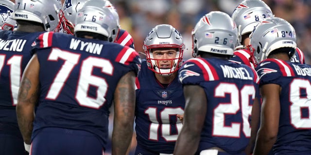 Quarterback New England Patriots Mac Jones, tengah, berkumpul dengan rekan satu tim selama paruh pertama pertandingan sepak bola NFL pramusim melawan Tim Sepak Bola Washington, Kamis, 12 Agustus 2022, di Foxborough, Mass. (AP Photo/Steven Senne)