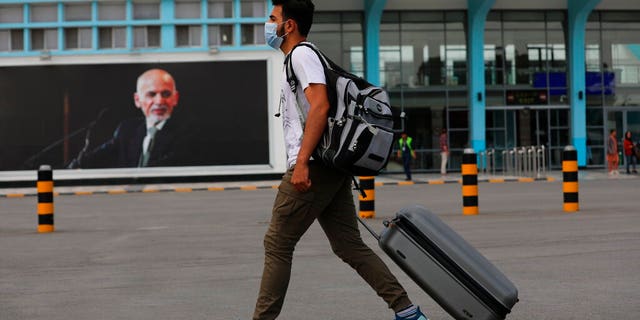 A passenger walks to the departures terminal of Hamid Karzai International Airport, in Kabul, Afghanistan, Saturday, Aug. 14, 2021. As a Taliban offensive encircles the Afghan capital, there's increasingly only one way out for those fleeing the war, and only one way in for U.S. troops sent to protect American diplomats still on the ground: the airport. (AP Photo/Rahmat Gul)