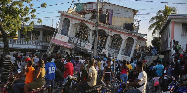 People gather outside the Petit Pas Hotel, destroyed by the earthquake in Les Cayes, Haiti, Saturday, Aug. 14, 2021. A 7.2 magnitude earthquake struck Haiti on Saturday, with the epicenter about 125 kilometers (78 miles) west of the capital of Port-au-Prince, the US Geological Survey said.