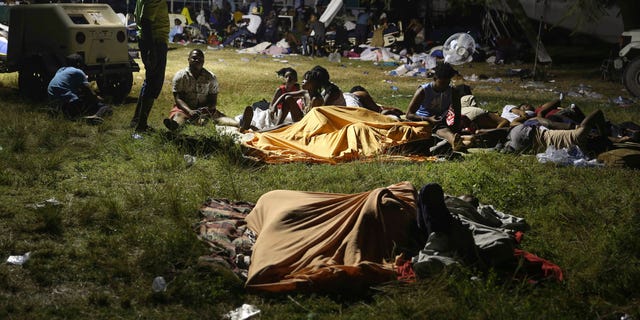 People displaced from their earthquake destroyed homes spend the night outdoors in a grassy area that is part of a hospital in Les Cayes, Haiti, late Saturday, Aug. 14, 2021. A powerful magnitude 7.2 earthquake struck southwestern Haiti on Saturday. (AP Photo/Joseph Odelyn)