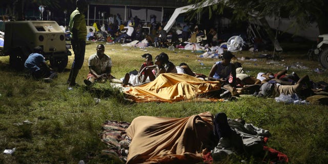 People displaced from their earthquake destroyed homes spend the night outdoors in a grassy area that is part of a hospital in Les Cayes, Haiti, late Saturday, Aug. 14, 2021. A powerful magnitude 7.2 earthquake struck southwestern Haiti on Saturday. (AP Photo/Joseph Odelyn)