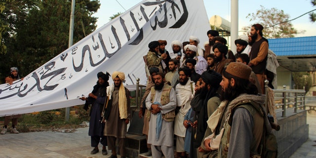 Des combattants talibans posent pour une photo tout en levant leur drapeau Des combattants talibans lèvent leur drapeau dans la maison du gouverneur de la province de Ghazni, à Ghazni, dans le sud-est de l'Afghanistan, le dimanche 15 août 2021. (AP Photo/Gulabuddin Amiri)
