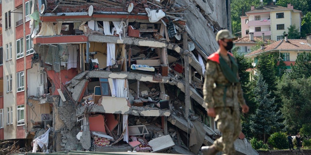 A soldier walks on a temporary bridge set up by military in Bozkurt town of Kastamonu province, Turkey, Sunday, Aug. 15, 2021, after flooding. Turkey sent ships to help evacuate people and vehicles from a northern town on the Black Sea that was hard hit by flooding, as the death toll in the disaster rose Sunday to at least 62 and more people than that remained missing. (AP Photo)