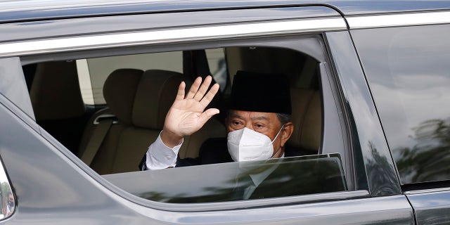 Embattled Malaysian Prime Minister Muhyiddin Yassin waves from a car while entering the National Palace to meet with the King in Kuala Lumpur, Malaysia, Monday, Aug. 16, 2021. (AP Photo/FL Wong)