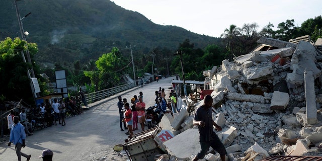 A man walks on a collapsed building in Saint-Louis-du-Sud, Haiti, Monday, Aug. 16, 2021, two days after a 7.2-magnitude earthquake struck the southwestern part of the hemisphere's poorest nation on Aug. 14.(AP Photo/Matias Delacroix)