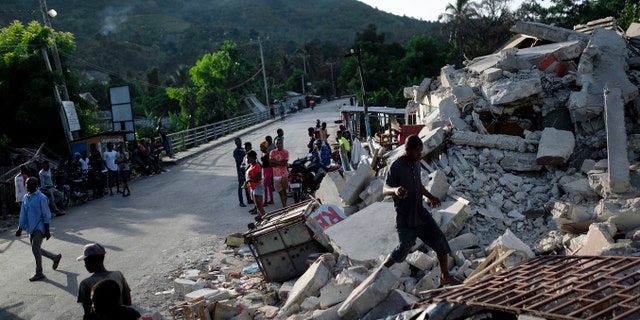 A man walks on a collapsed building in Saint-Louis-du-Sud, Haiti, Monday, Aug. 16, 2021, two days after a 7.2-magnitude earthquake struck the southwestern part of the hemisphere's poorest nation on Aug. 14.(AP Photo/Matias Delacroix)
