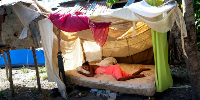 A woman sleeps outside her home in Saint-Louis-du-Sud, Haiti, Monday, Aug. 16, 2021, two days after a 7.2-magnitude earthquake struck the southwestern part of the country. (AP Photo/Matias Delacroix)