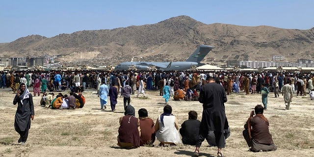 Hundreds of people gather near a US Air Force C-17 transport plane in the perimeter of Kabul International Airport, Afghanistan on Monday, August 16, 2021. (AP Photo / Shekib Rahmani)