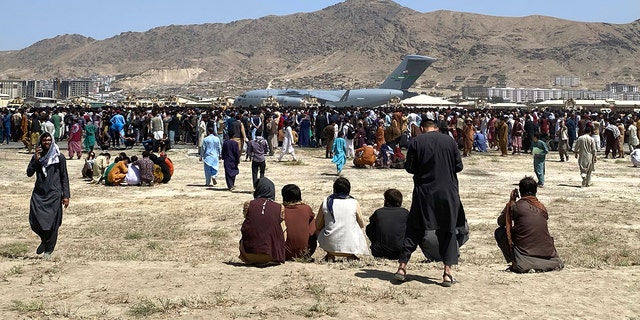 Hundreds of people gather near a US Air Force C-17 transport plane at the perimeter of Kabul International Airport in Afghanistan on Monday, August 16, 2021. (AP Photo / Shekib Rahmani)