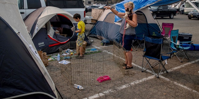 Julie Price points while talking to another evacuee at the Green Valley Community Church evacuation shelter on Thursday, Aug. 19, 2021, in Placerville, Calif., after fleeing the Caldor Fire. (AP Photo/Ethan Swope)