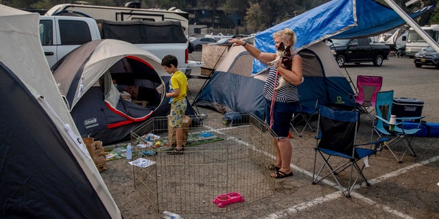Julie Price points while talking to another evacuee at the Green Valley Community Church evacuation shelter on Thursday, Aug. 19, 2021, in Placerville, Calif., after fleeing the Caldor Fire. (AP Photo/Ethan Swope)