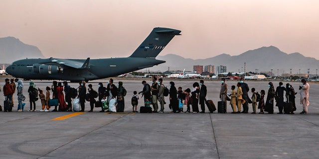 Evacuees wait to board a Boeing C-17 Globemaster III, at Hamid Karzai International Airport, Kabul, Afghanistan, Monday, Aug. 23, 2021.
