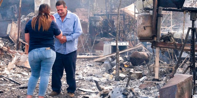 Homeowner Jose Lamas, 正しい, and his daughter Astrid Covarrubias survey the charred debris left in his burned-out home from the South Fire in Lytle Creek, San Bernardino County, north of Rialto, カリフォルニア, 水曜日, 8月. 25, 2021.