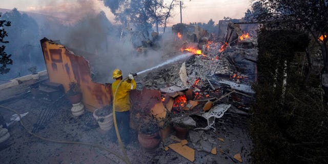 A firefighter tries to extinguish the flames at a burning house as the South Fire burns in Lytle Creek, San Bernardino County, north of Rialto, カリフォルニア, 水曜日, 8月. 25, 2021. 