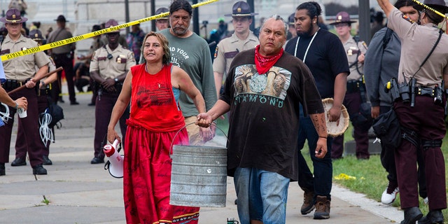 Two activists, who identify as water protectors, carry away the coals of a ceremonial fire after being removed from the site of a protest opposing the Enbridge Line 3 oil pipeline at the Minnesota Statehouse in St. Paul, Minn., Friday, Aug. 27, 2021. (Associated Press)