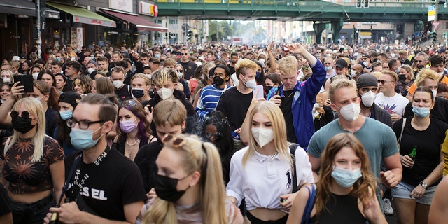People, most of them wearing masks, dance behind a truck as they attend a demonstration named 'Train of Love' in Berlin, Germany, Saturday, Aug. 28, 2021. 