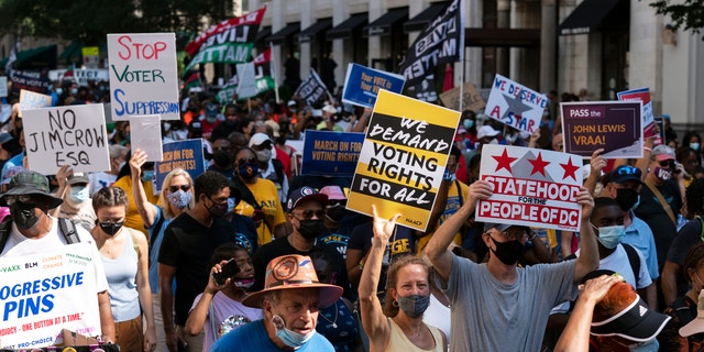 Demonstrators hold signs during a march for voting rights, marking the 58th anniversary of the March on Washington, Saturday, Aug. 28, 2021, in Washington. (AP Photo/Jose Luis Magana)
