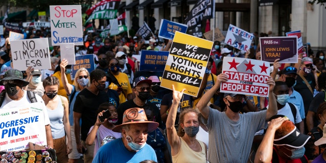 Demonstrators hold signs during a march for voting rights, marking the 58th anniversary of the March on Washington, Saturday, Aug. 28, 2021, in Washington. (AP Photo/Jose Luis Magana)