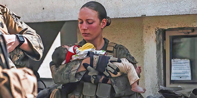 In this Aug. 20, 2021, image provided by the U.S. Marine Corps, Marines assigned to the 24th Marine Expeditionary Unit (MEU), including Sgt. Nicole Gee calms an infant during an evacuation at Hamid Karzai International Airport in Kabul, Afghanistan. Officials said Aug. 28, that Gee of Sacramento, Calif., was one of the Marines killed in Thursday's bombing at the airport. 