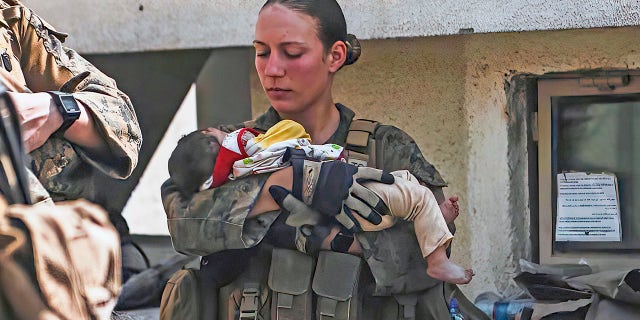 In this Aug. 20, 2021, image provided by the U.S. Marine Corps, Marines assigned to the 24th Marine Expeditionary Unit (MEU), including Sgt. Nicole Gee calms an infant during an evacuation at Hamid Karzai International Airport in Kabul, Afghanistan. Officials said Aug. 28, that Gee of Sacramento, Calif., was one of the Marines killed in Thursday's bombing at the airport.