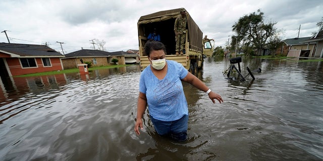Jerilyn Collins wades through floodwaters Monday after being transported by the Louisiana National Guard back to her home to retrieve medicine for herself and her father, after she evacuated from rising water in the aftermath of Hurricane Ida in LaPlace, La.
