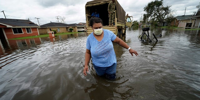 Jerilyn Collins wades through floodwaters Monday after being transported by the Louisiana National Guard back to her home to retrieve medicine for herself and her father, after she evacuated from rising water in the aftermath of Hurricane Ida in LaPlace, La.