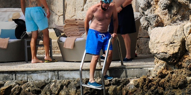 Adam Sandler mixes a little business and pleasure as he takes a break from his filming duties on the beach in Palma De Mallorca.