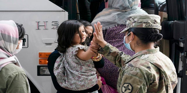 Army Pfc. Kimberly Hernandez gives a high-five to a girl evacuated from Kabul, Afghanistan, before boarding a bus after they arrived at Washington Dulles International Airport, in Chantilly, Va., on Monday.
