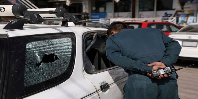 An Afghan police officer inspects the car after director of Afghanistan's Government Information Media Center Dawa Khan Menapal was shot dead in Kabul, Afghanistan, on Friday. 