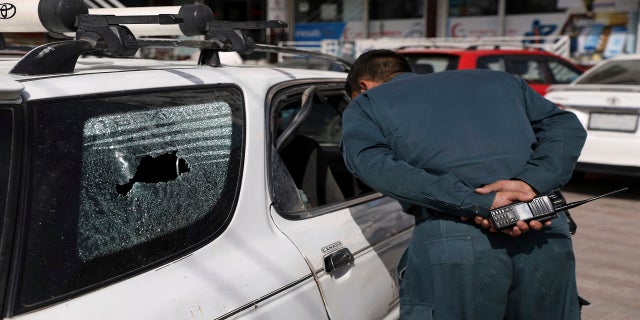 An Afghan police officer inspects the car after the director of the Afghan Government Information Center, Dawa Khan Menapal, was shot dead in Kabul, Afghanistan on Friday.