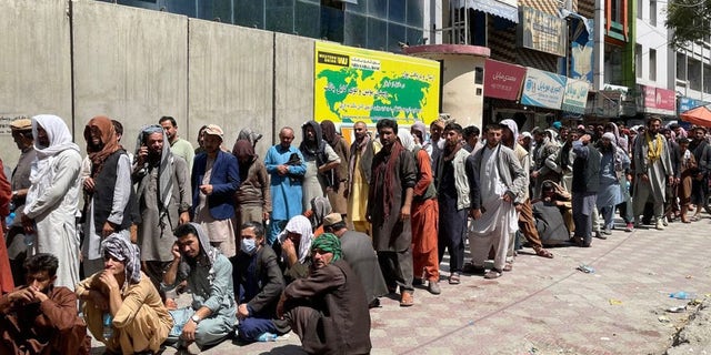 Afghans line up outside a bank to take out cash as people keep waiting at Hamid Karzai International Airport to leave the country after Taliban's takeover in Kabul, Afghanistan, on August 25, 2021.