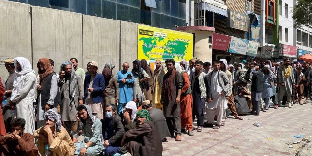Afghans line up outside a bank to take out cash as people keep waiting at Hamid Karzai International Airport to leave the country after Taliban's takeover in Kabul, Afghanistan, on August 25, 2021.