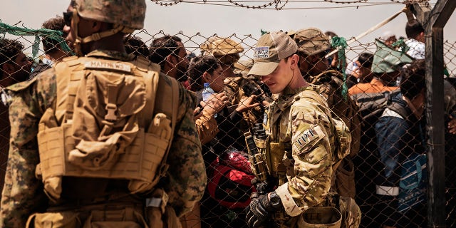 In a photo shared by the U.S. Marine Corps, U.S. service members provide assistance during an evacuation at Hamid Karzai International Airport, Kabul, Afghanistan, on Sunday, Aug. 22, 2021.