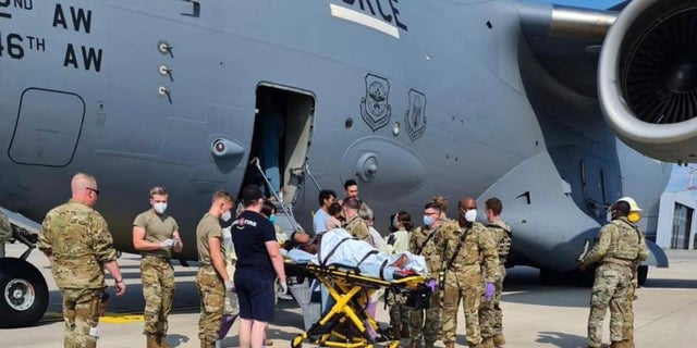 Air Force personnel help an Afghan reugree at Ramstein Air Base in Germany, where she gave birth over the weekend after fleeing Afghanistan. Officials said Monday that three babies have been born amid evacuation efforts.