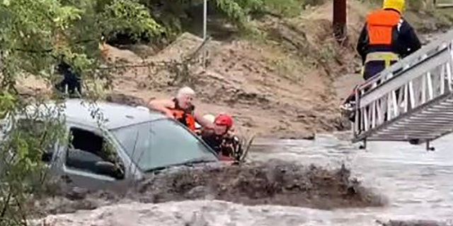 Rescuers pulled a woman to safety after she became trapped inside a vehicle amid a flash flood near Tucson, Ariz., on Tuesday.