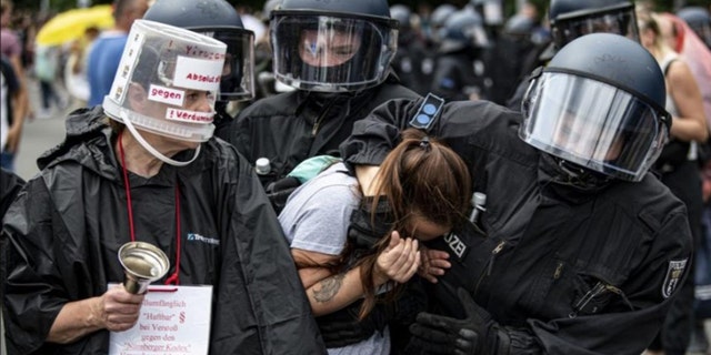 La police arrête un manifestant lors d'une manifestation non annoncée à la Colonne de la Victoire, à Berlin, le dimanche 1er août 2021, lors d'une manifestation contre les restrictions liées aux coronavirus.  (Fabian Sommer/dpa via AP)