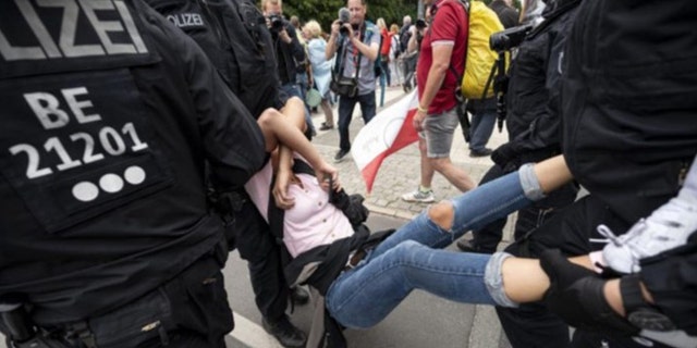 La policía arresta a un manifestante en una protesta no anunciada en la Columna de la Victoria en Berlín el domingo 1 de agosto de 2021, durante una protesta contra las restricciones del coronavirus.  (Fabian Sommer / dpa vía AP)