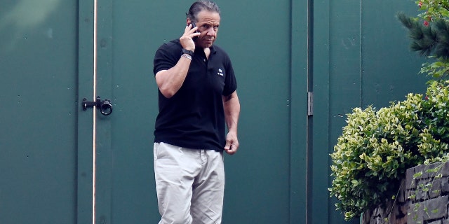 Gov. Andrew Cuomo talks on the phone while walking with his dog Captain at the New York state Executive Mansion, Saturday, Aug. 7, 2021, in Albany, N.Y.