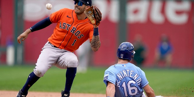 The Kansas City Royals' Andrew Benintendi (16) is caught stealing second by Houston Astros shortstop Carlos Correa (1) during a game Thursday, Aug. 19, 2021, in Kansas City, Mo.