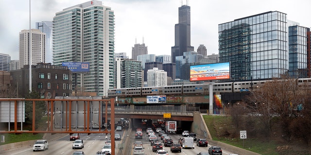 Traffic flows along the Interstate 90 highway in March 2021 as a Metra suburban commuter train moves along an elevated track in Chicago. 