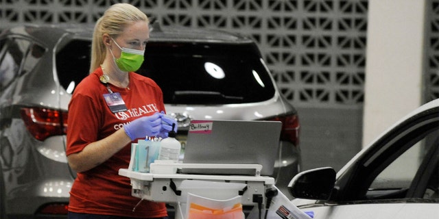 A worker from USA Health prepares to vaccinate a person for COVID-19 during a drive-up clinic in Mobile, Ala., on Thursday, Aug. 12, 2021. (AP Photo/Jay Reeves)
