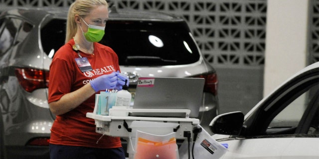 A worker from USA Health prepares to vaccinate a person for COVID-19 during a drive-up clinic in Mobile, Alabama, on Aug. 12, 2021. 