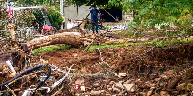 A man clears debris on property along the East Fork Pigeon River in Cruso, N.C., Friday, Aug. 20, 2021, after remnants from Tropical Storm Fred caused flooding in parts of Western North Carolina on Tuesday. 